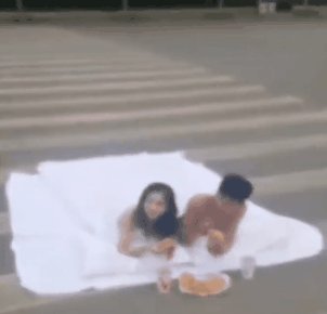 男女裹床单躺斑马线拍婚纱照 另有一名女子专挡道
